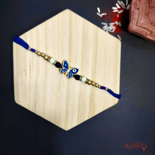 Blue evil eye butterfly rakhi with golden beads ona wooden background