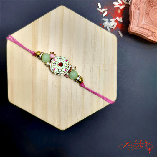 Pista green rakhi with circular white meenakari centerpiece and green beads , on a light wooden hexagon