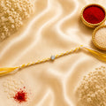 Minimal Solitaire Stone Bhai Rakhi featuring a sparkling crystal centerpiece in a gold-toned bezel with a yellow and white braided thread by Kashika JewelCrafts.
