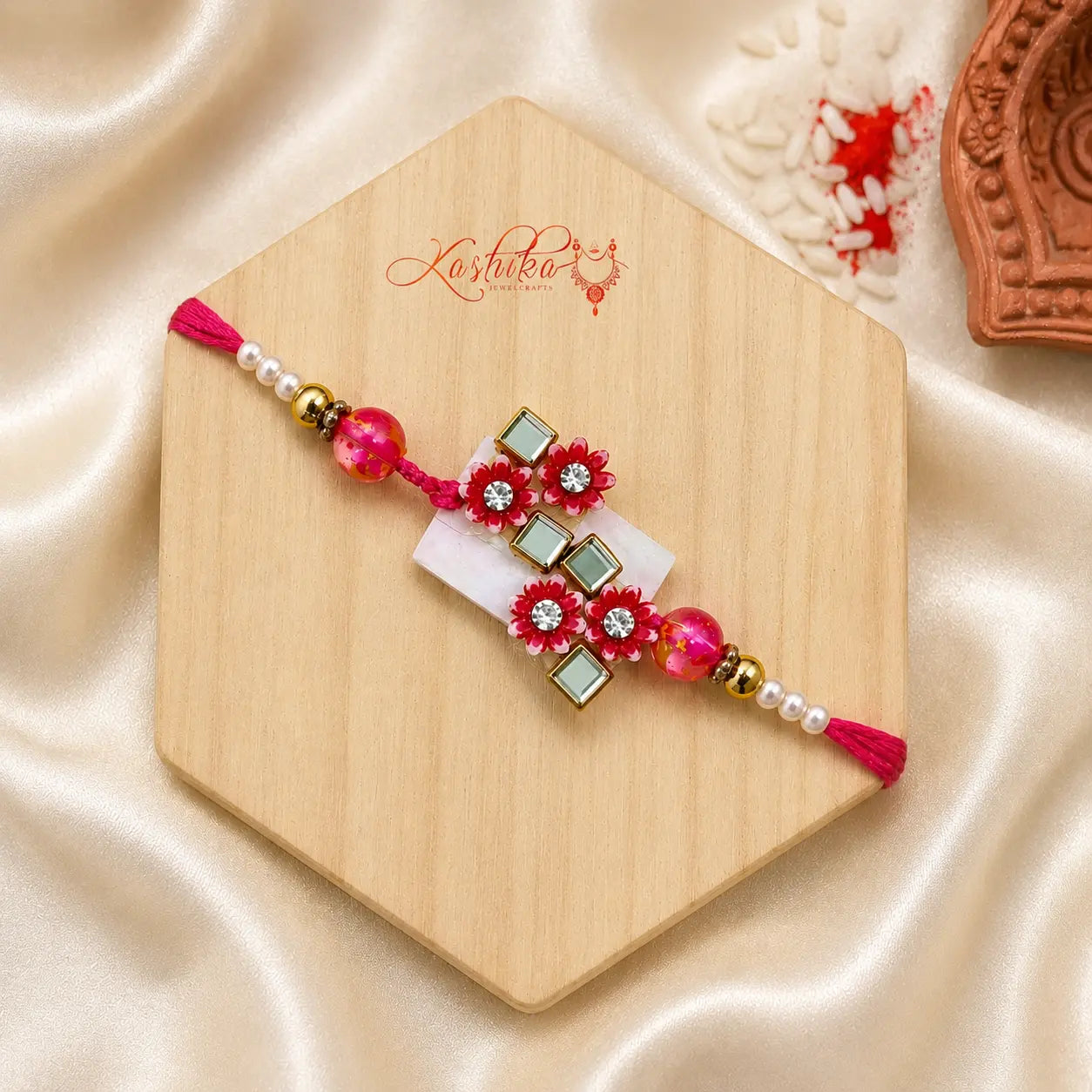 Pink Floral Mirror Bhai Rakhi handcrafted with crystal stones, mirror work, pink beads, and pearl accents by Kashika JewelCrafts.