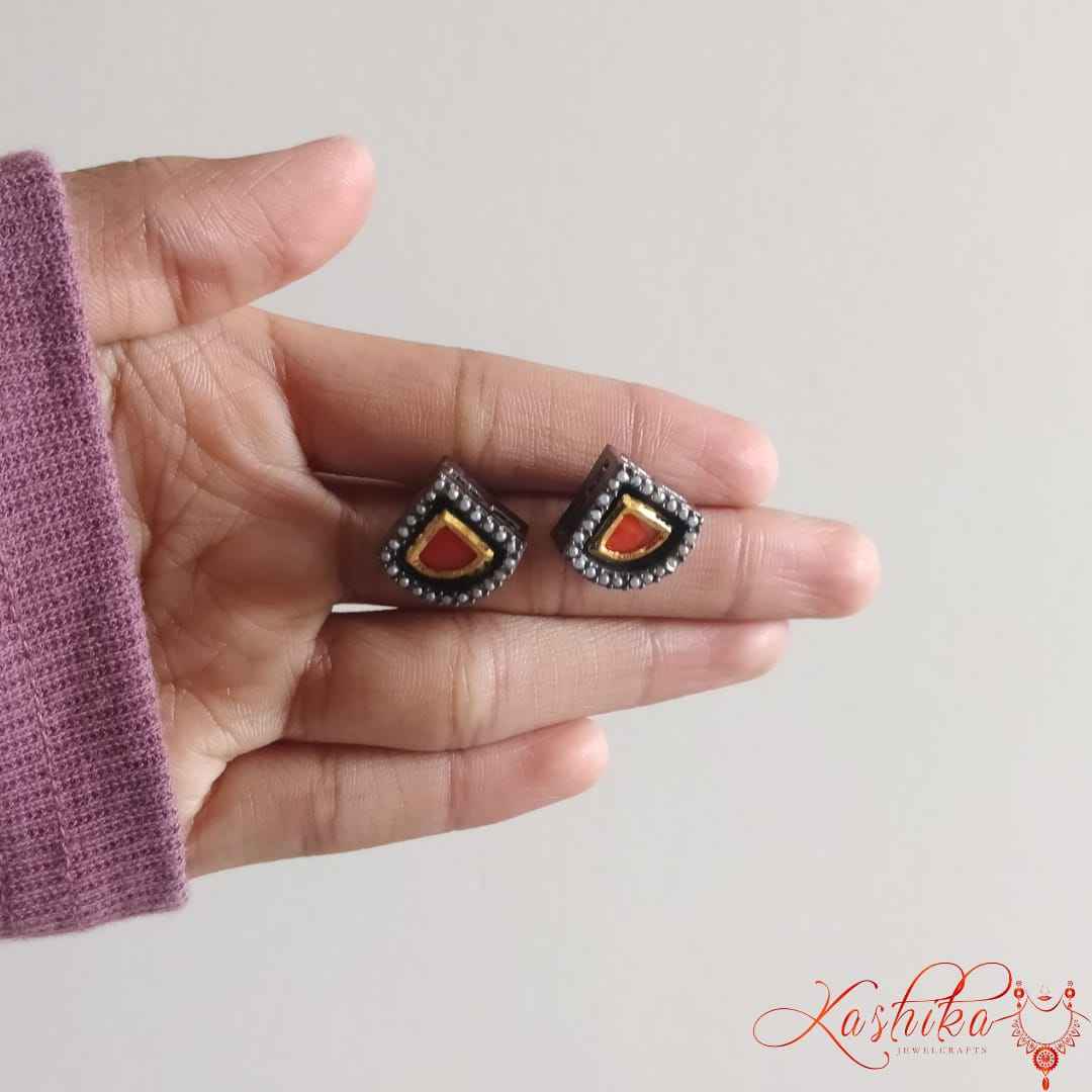 Oxidised stud earrings with teardrop shaped red gemstone bordered by gold and silver detailing - Kashika JewelCrafts