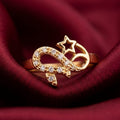 Gold ring with star and snake design on a red fabric background