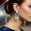 Close-up of a woman wearing a blue earring with a blurred background