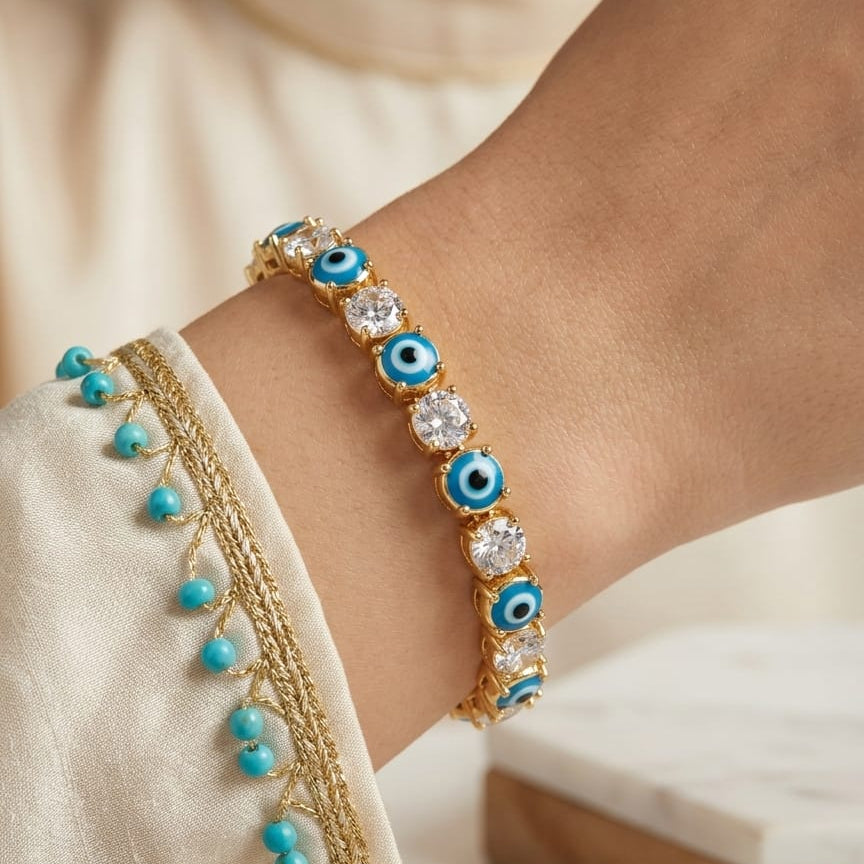 Bracelet with blue and clear gemstones on a wrist, wearing a white garment.