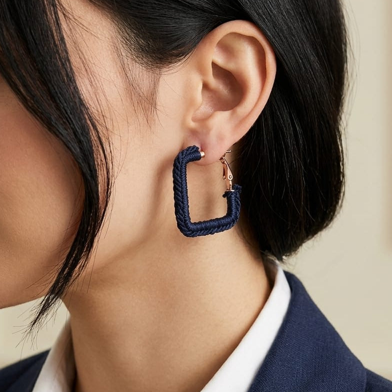 Close-up of a woman wearing a blue hoop earring with a neutral background