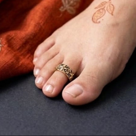 Close-up of a foot with a ring on a textured surface