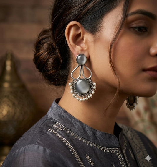 Close-up of a woman wearing large, ornate earrings with a blurred background