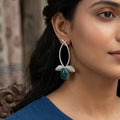 Woman wearing blue earrings with a blurred background