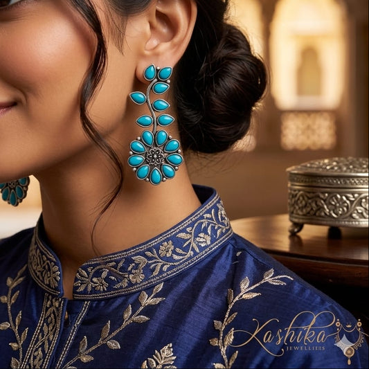 Woman wearing turquoise floral earrings with a blurred background