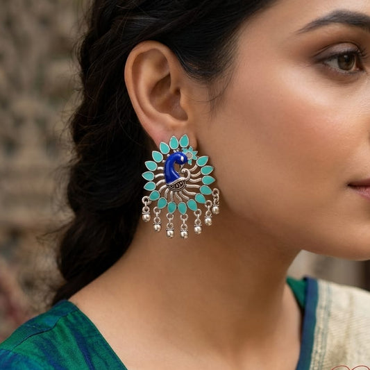 Woman wearing a pair of large, decorative earrings with a blurred background